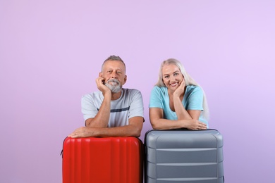 Senior couple with suitcases on color background. Vacation travel