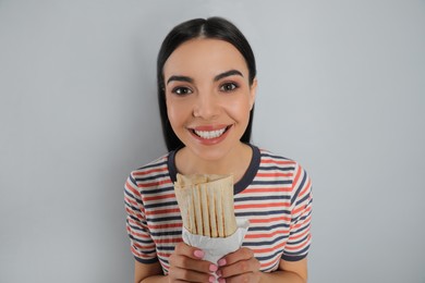 Photo of Happy young woman with delicious shawarma on grey background