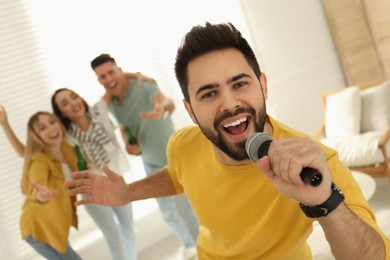 Young man singing karaoke with friends at home