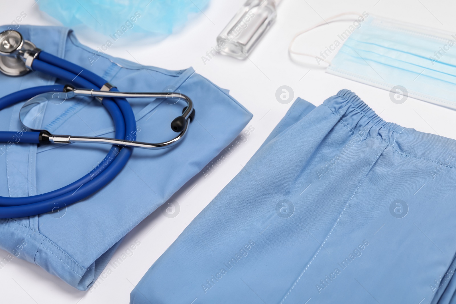 Photo of Medical uniform, face mask, stethoscope and antiseptic on white background, closeup view