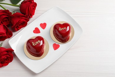Photo of St. Valentine's Day. Delicious heart shaped cakes and roses on table, top view. Space for text