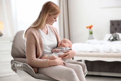 Photo of Mother with her little baby sitting in armchair at home