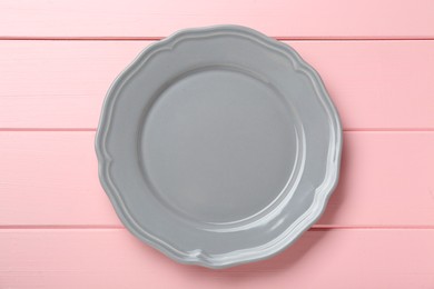 Empty grey ceramic plate on pink wooden table, top view