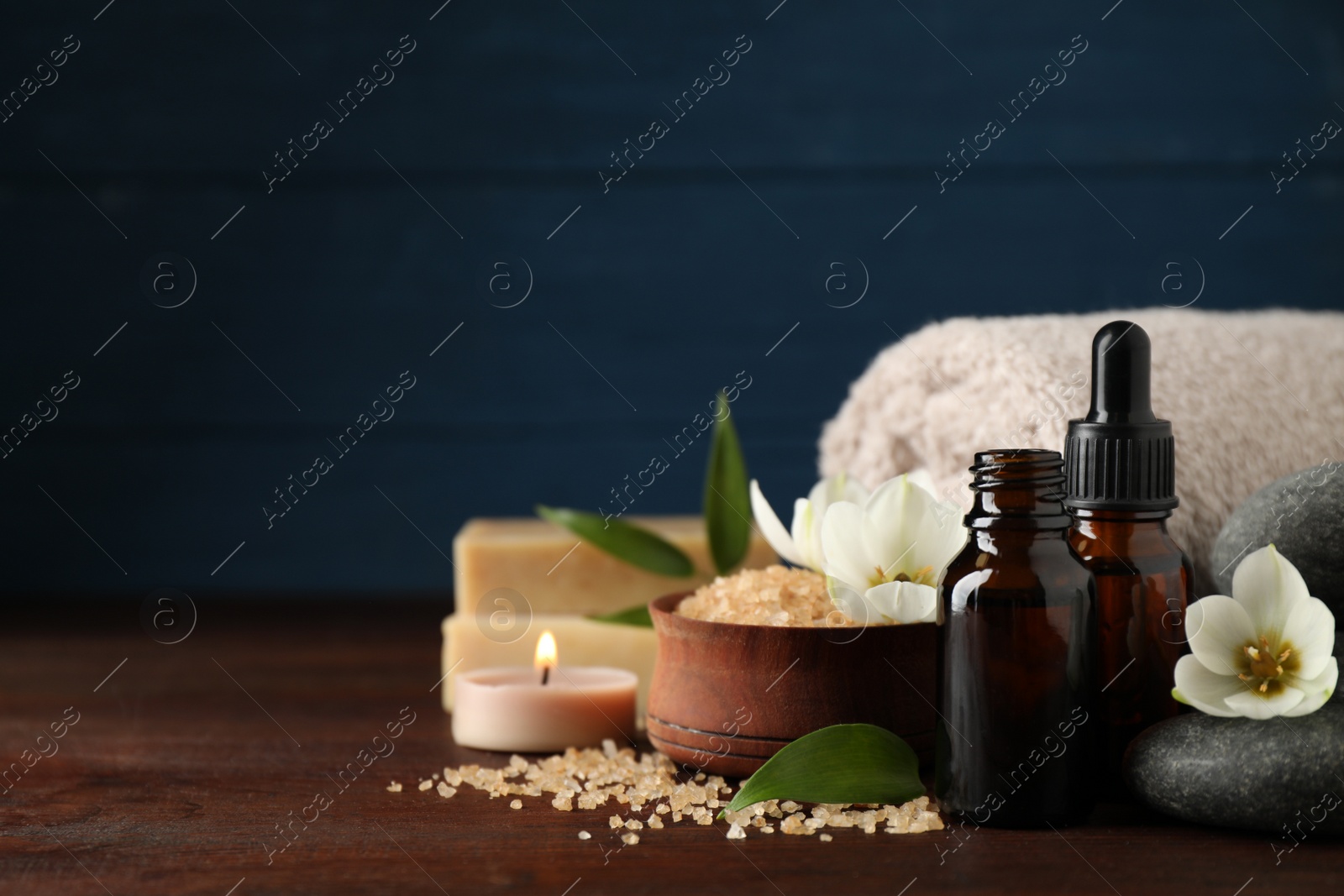 Photo of Composition with skin care products, spa stones and aroma oil on wooden table. Space for text
