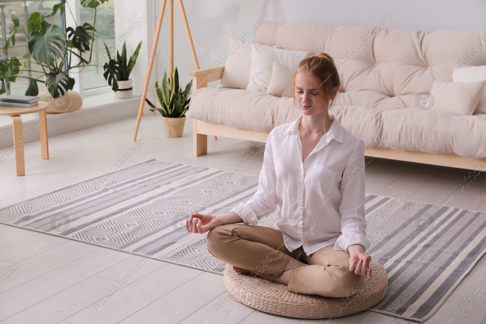 Photo of Woman meditating on wicker mat at home. Space for text