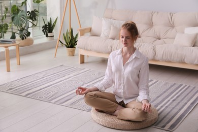 Woman meditating on wicker mat at home. Space for text