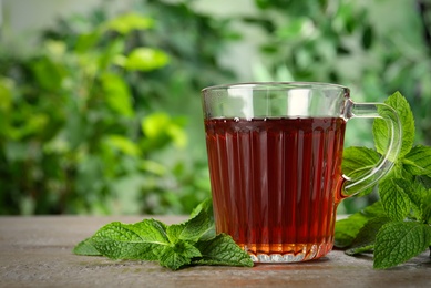 Photo of Fresh tea with mint leaves on wooden table. Space for text