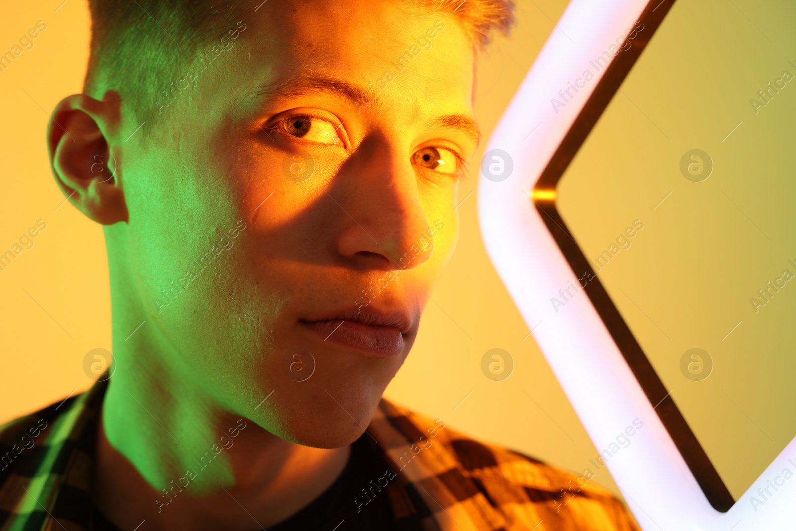 Photo of Young man with square lamp on color background in neon lights