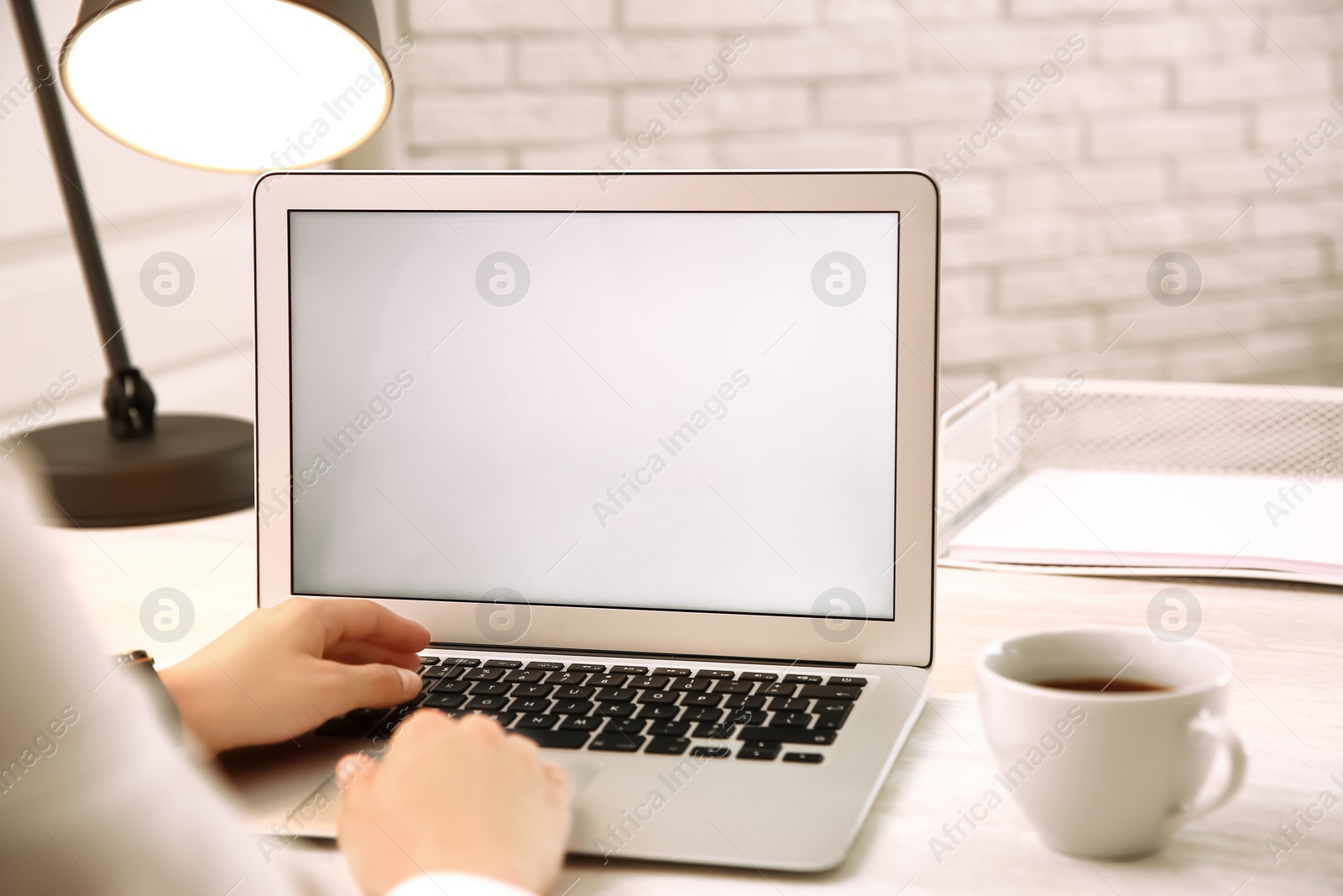 Photo of Woman working with modern laptop at white table, closeup. space for design