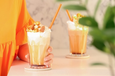 Photo of Woman with glass of delicious milk shake at table indoors