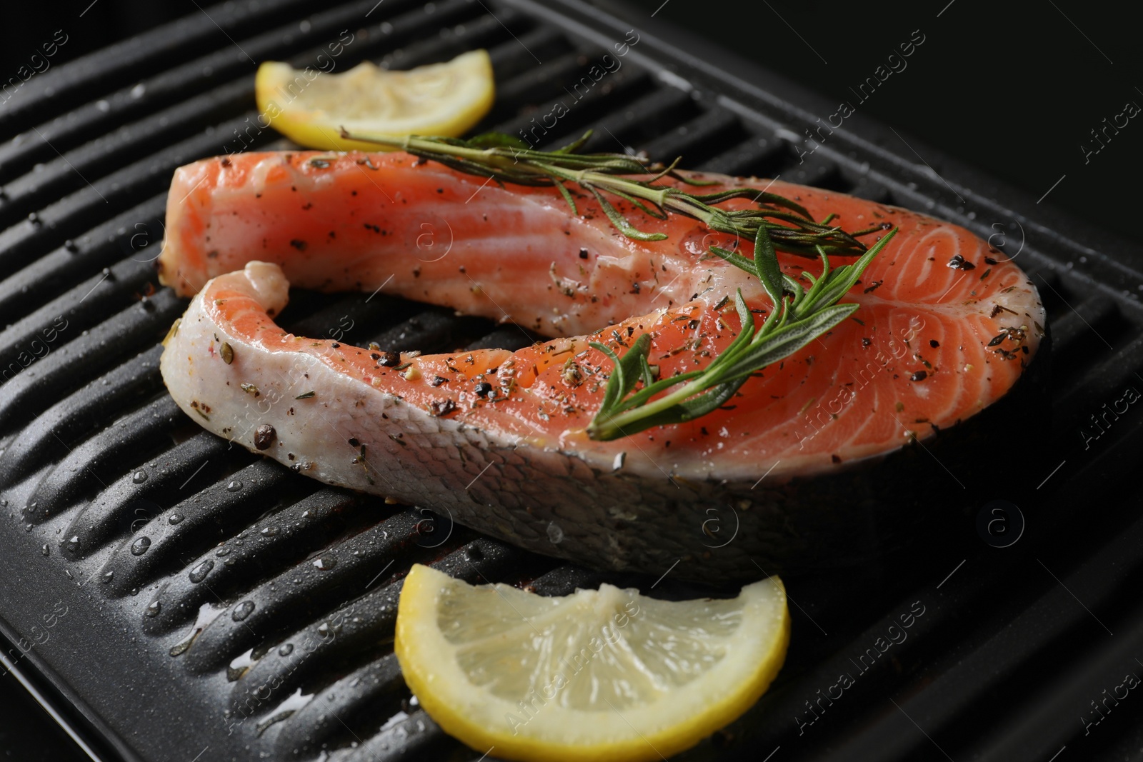 Photo of Cooking salmon. Grill with fresh fish steak, lemon and rosemary