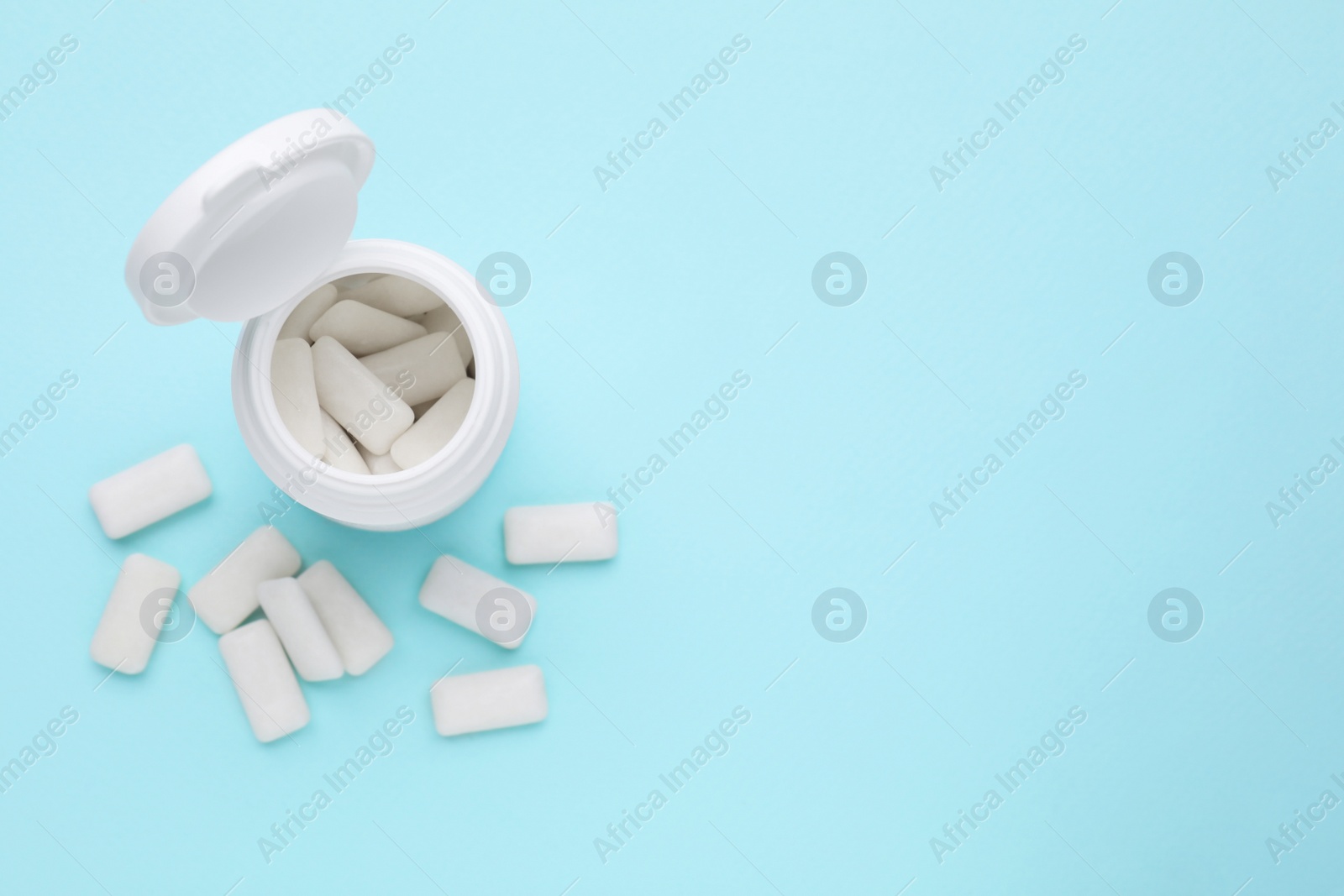 Photo of Jar with chewing gums on light blue background, flat lay. Space for text