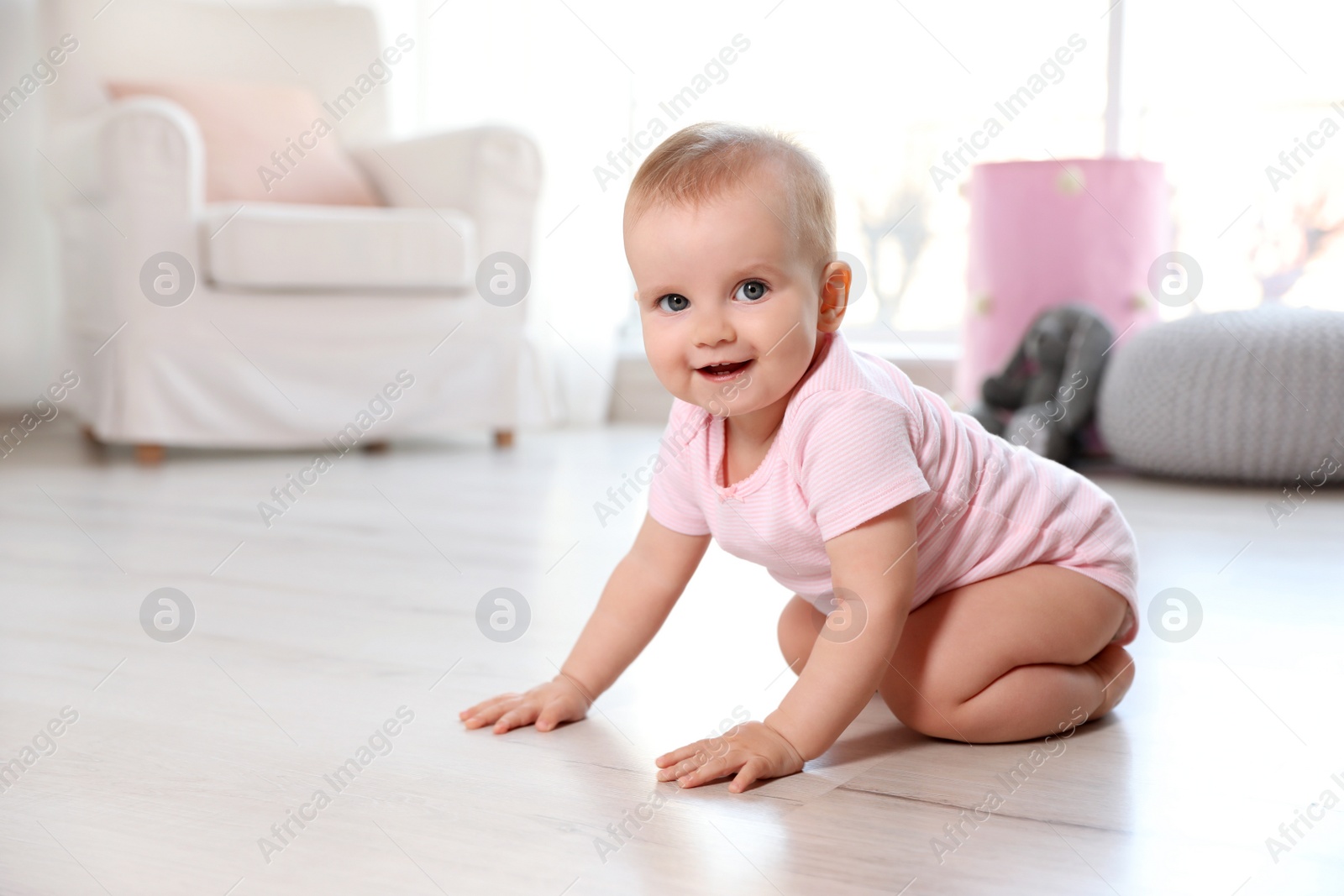 Photo of Cute baby girl sitting on floor in room