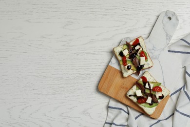 Photo of Delicious sandwiches with anchovy, cheese and tomato on white wooden table, top view. Space for text