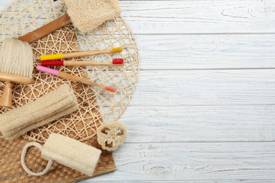 Photo of Flat lay composition with bamboo toothbrushes on white wooden table. Space for text