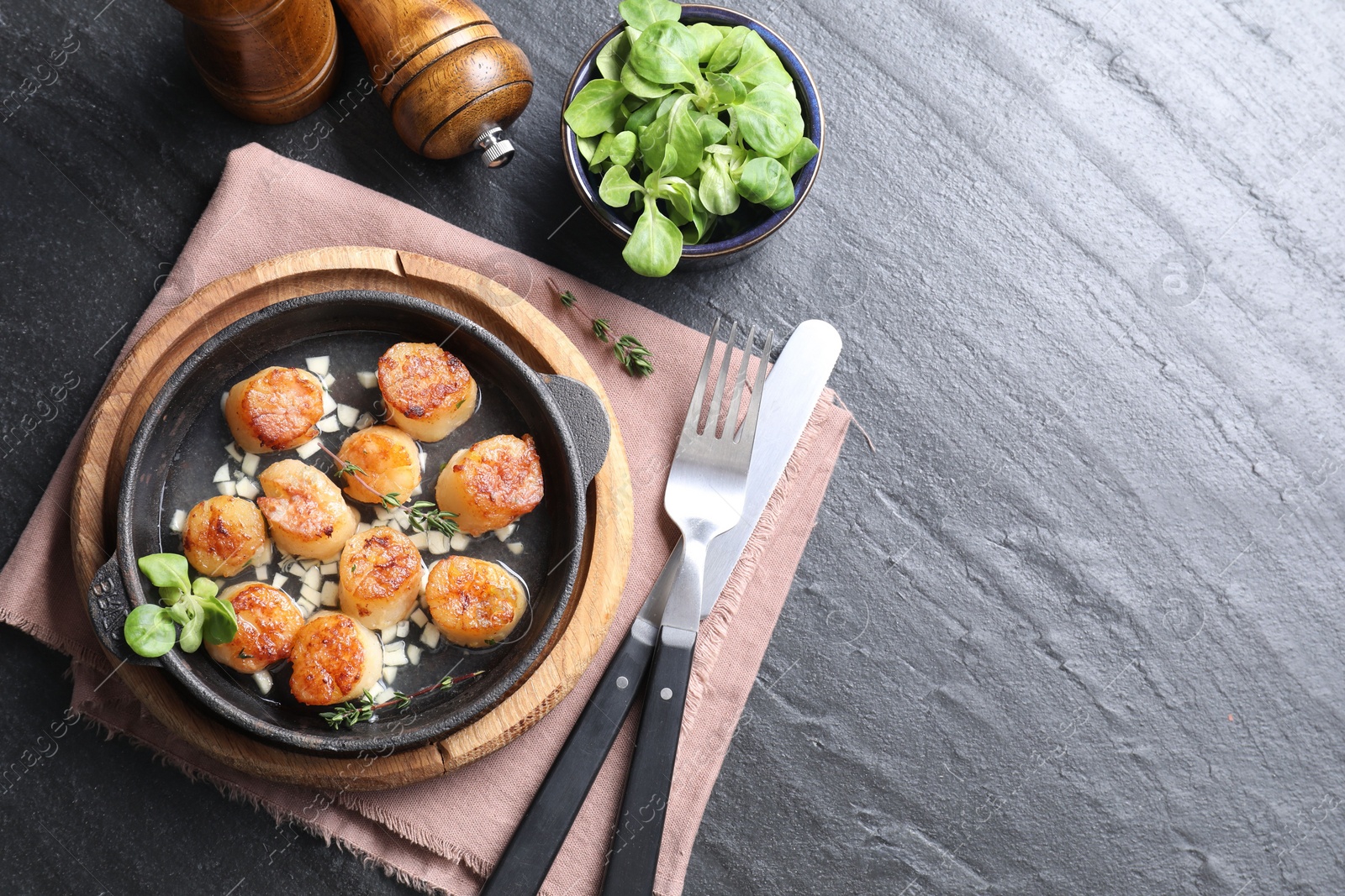 Photo of Delicious fried scallops in dish served on dark gray textured table, flat lay. Space for text