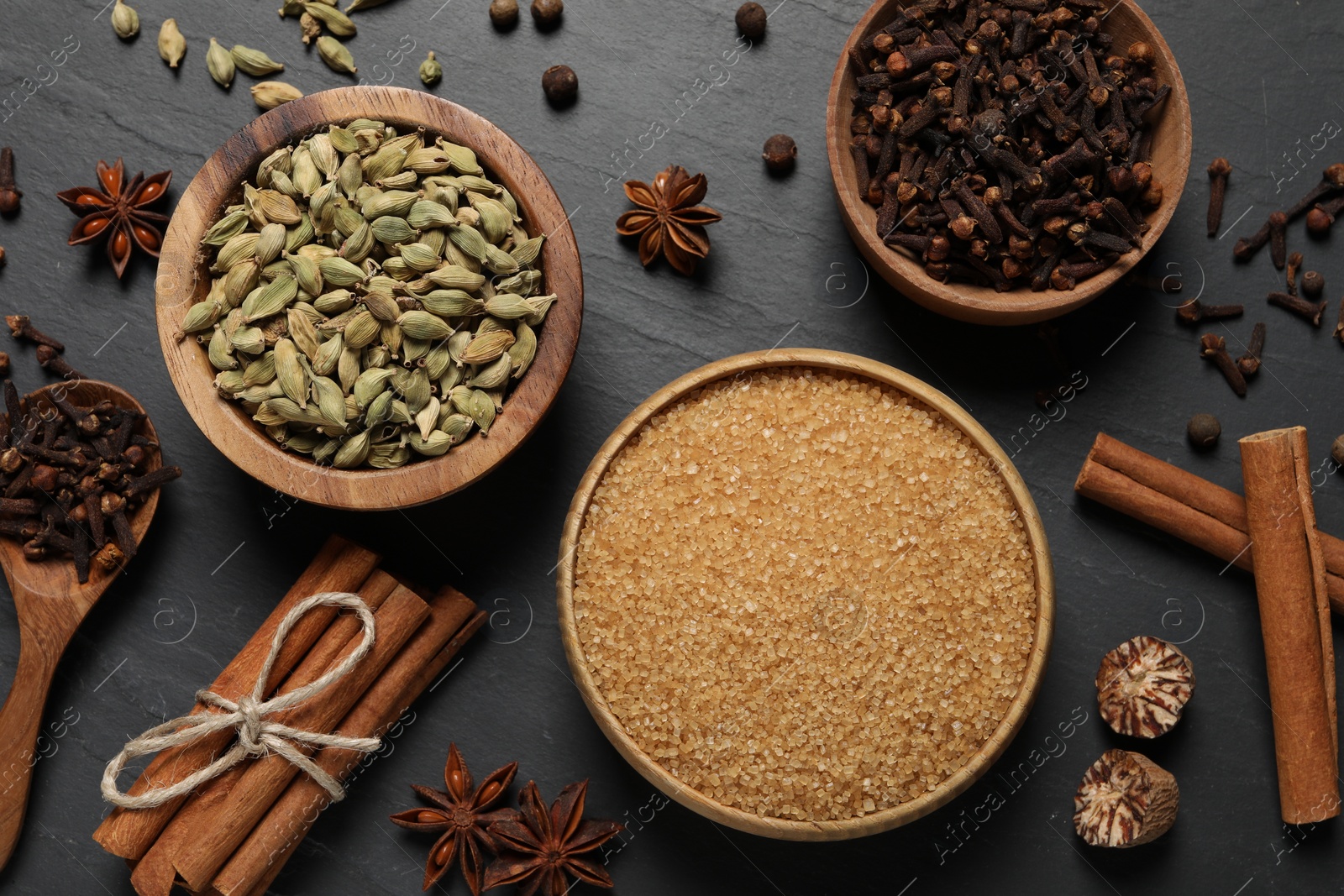 Photo of Different spices in bowls on dark gray textured table, flat lay