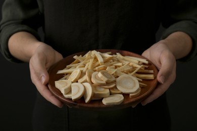 Woman holding plate with cut parsnips, closeup