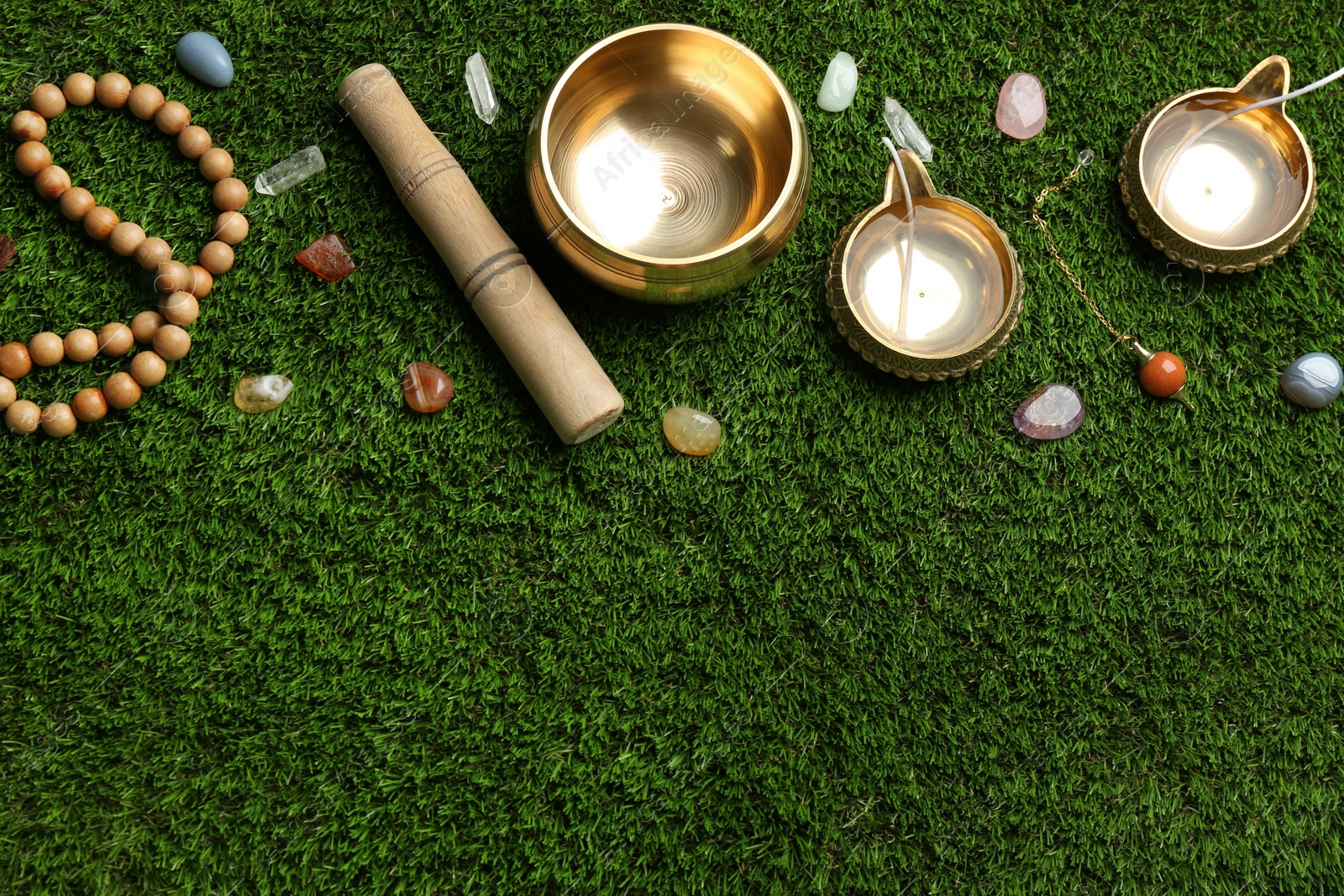 Photo of Flat lay composition with golden singing bowl on green grass, flat lay. Sound healing