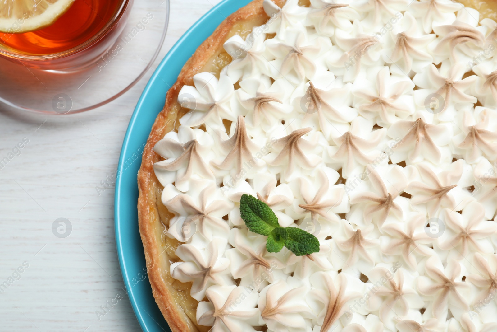 Photo of Delicious lemon meringue pie decorated with mint on white wooden table, flat lay