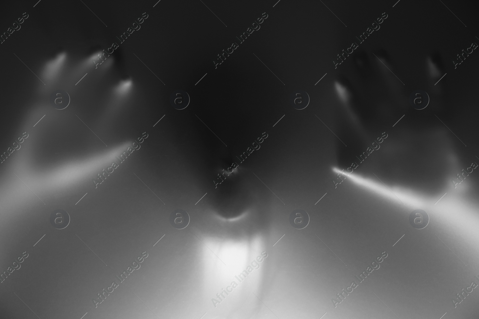 Photo of Silhouette of creepy ghost behind glass against grey background