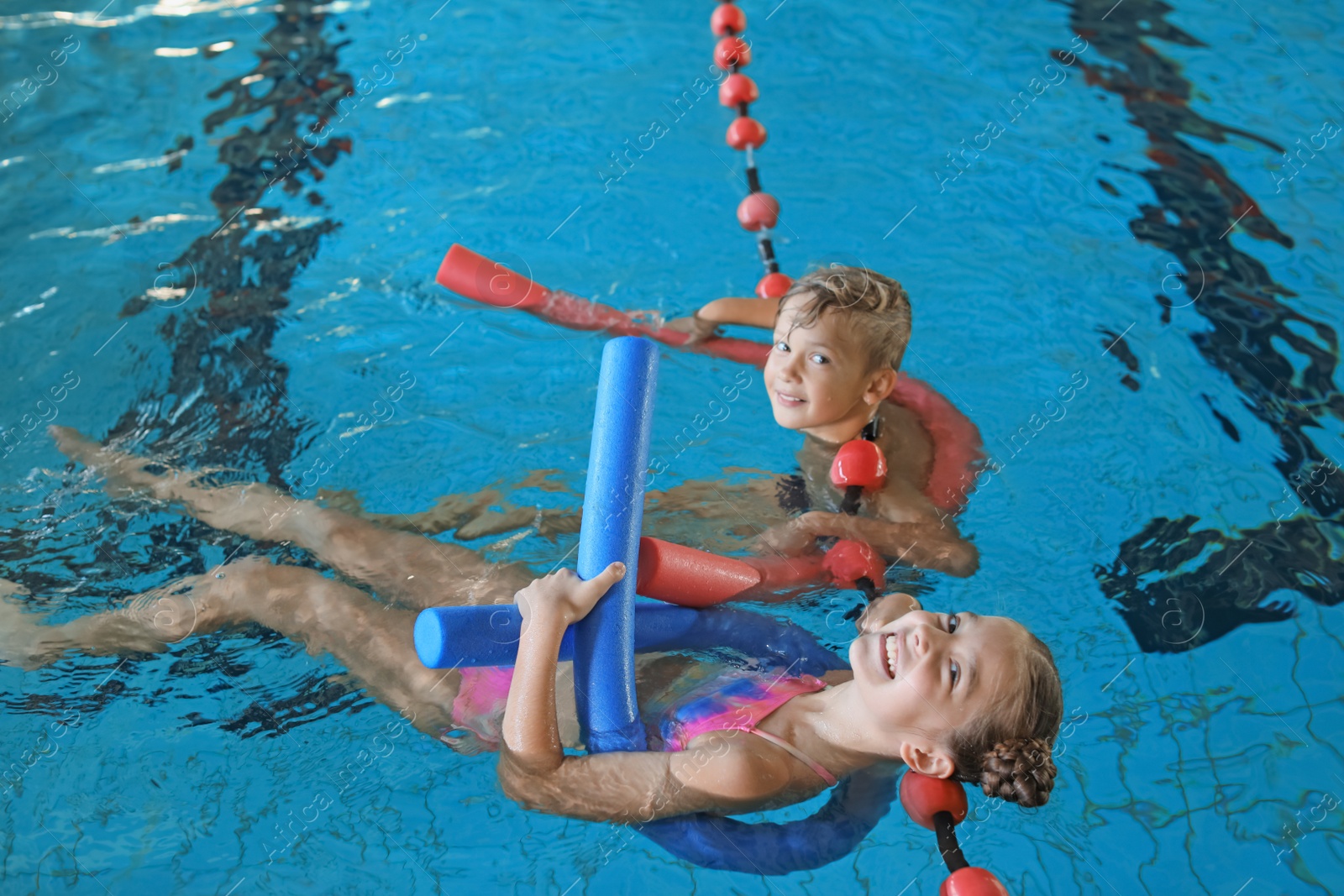 Photo of Little kids with swimming noodles in indoor pool