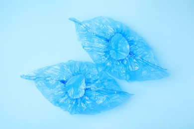 Photo of Pair of medical shoe covers on light blue background, top view