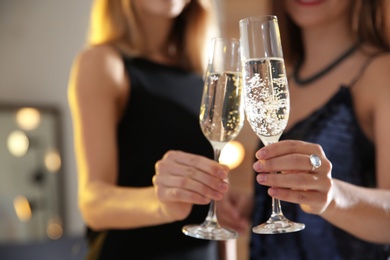 Photo of Friends clinking glasses with champagne at party indoors, closeup