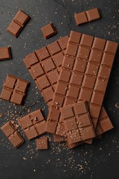 Pieces of tasty chocolate bars on grey table, flat lay