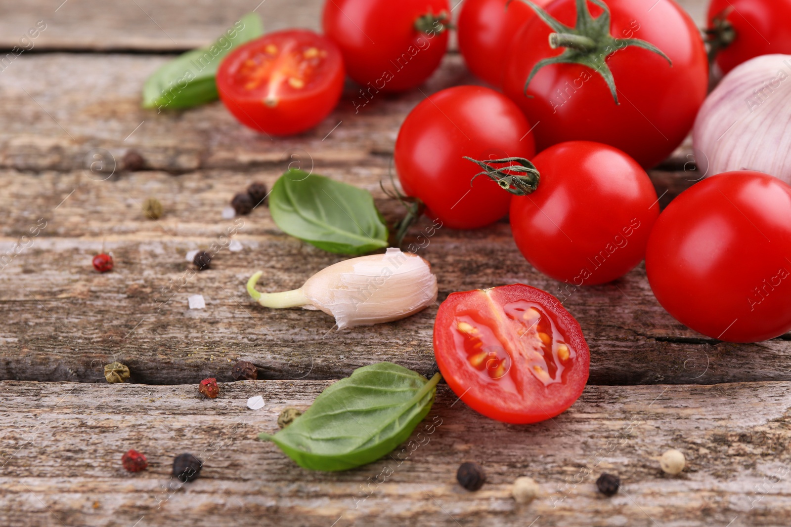 Photo of Ripe tomatoes, basil, garlic and spices on wooden table, closeup
