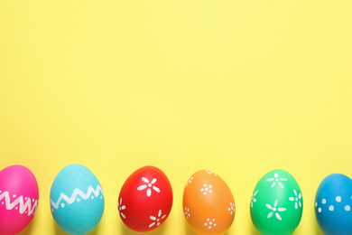 Photo of Colorful Easter eggs on yellow background, flat lay. Space for text