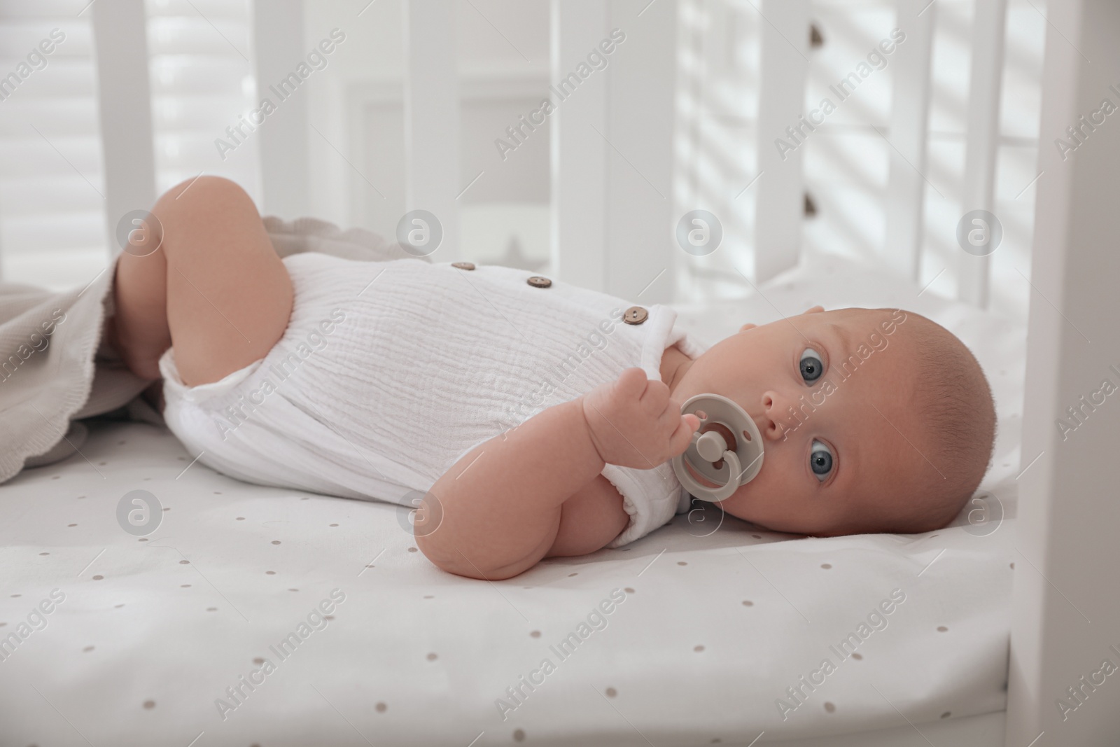 Photo of Cute little baby with pacifier lying on bed