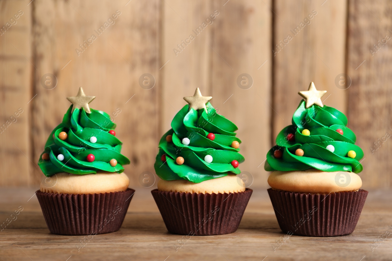 Photo of Christmas tree shaped cupcakes on wooden table