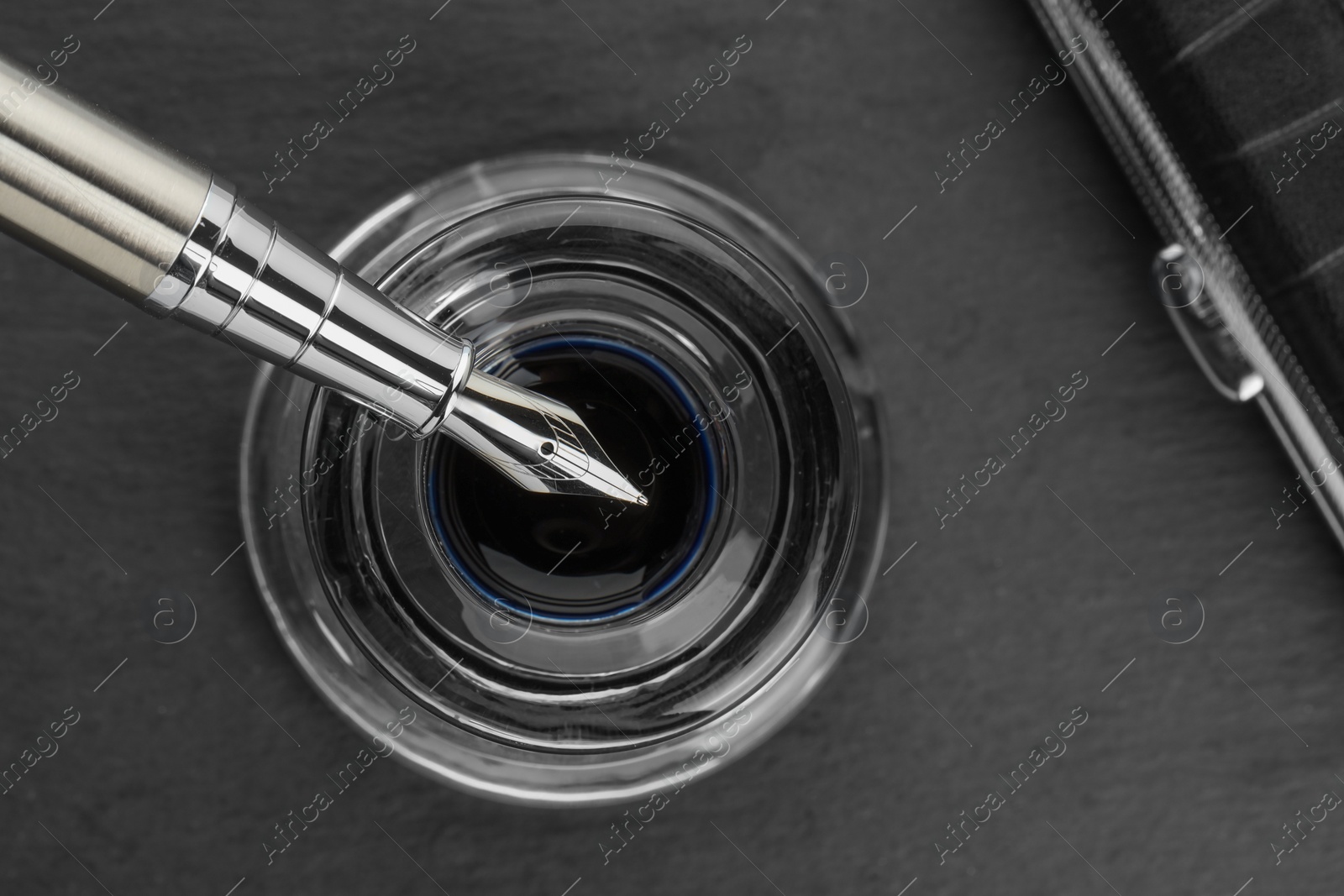 Photo of Inkwell with fountain pen on grey table, top view