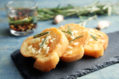 Photo of Slate plate with homemade garlic bread on table, closeup