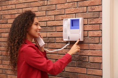 Photo of Young African-American woman answering intercom call indoors