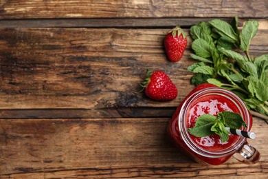 Photo of Tasty strawberry smoothie with mint in mason jar on wooden table, flat lay. Space for text