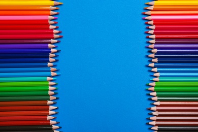 Photo of Color pencils on blue background, flat lay. Space for text