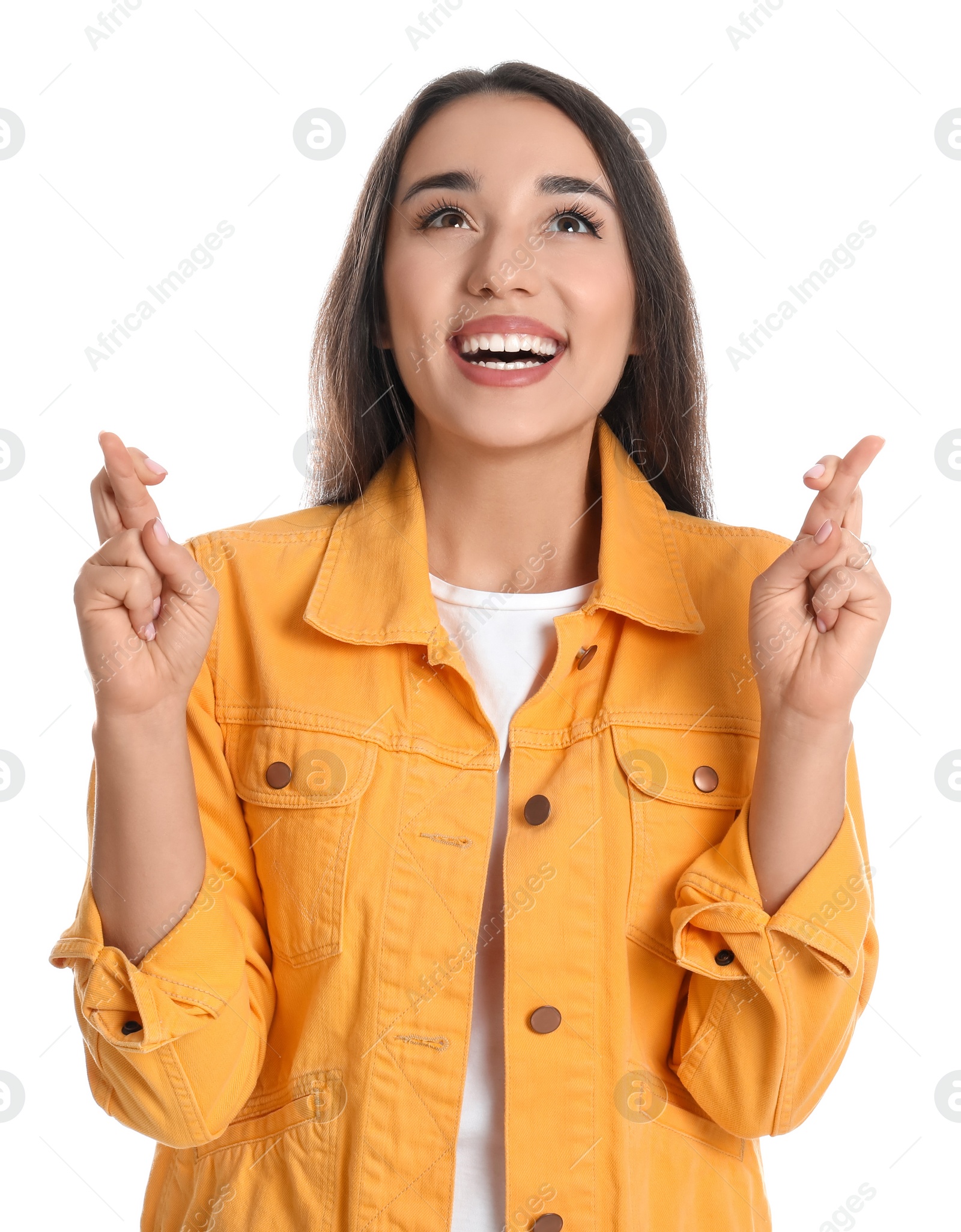 Photo of Excited young woman holding fingers crossed on white background. Superstition for good luck 