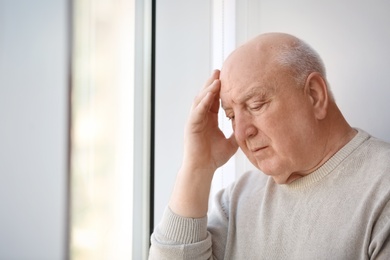 Photo of Depressed senior man near window indoors