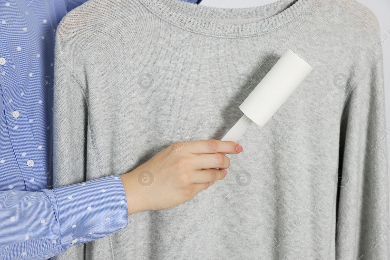 Photo of Woman cleaning clothes with lint roller, closeup