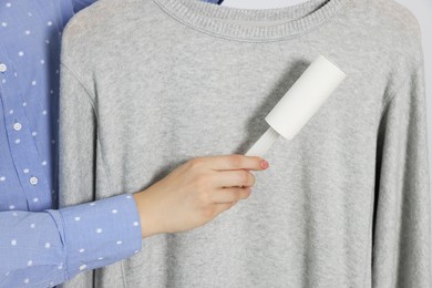 Woman cleaning clothes with lint roller, closeup