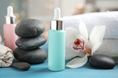 Beautiful spa composition with essential oil and orchid flower on turquoise table against blurred lights