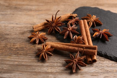 Photo of Aromatic cinnamon sticks and anise stars on wooden table, closeup