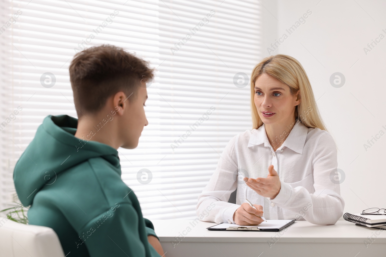 Photo of Psychologist working with teenage boy at table in office