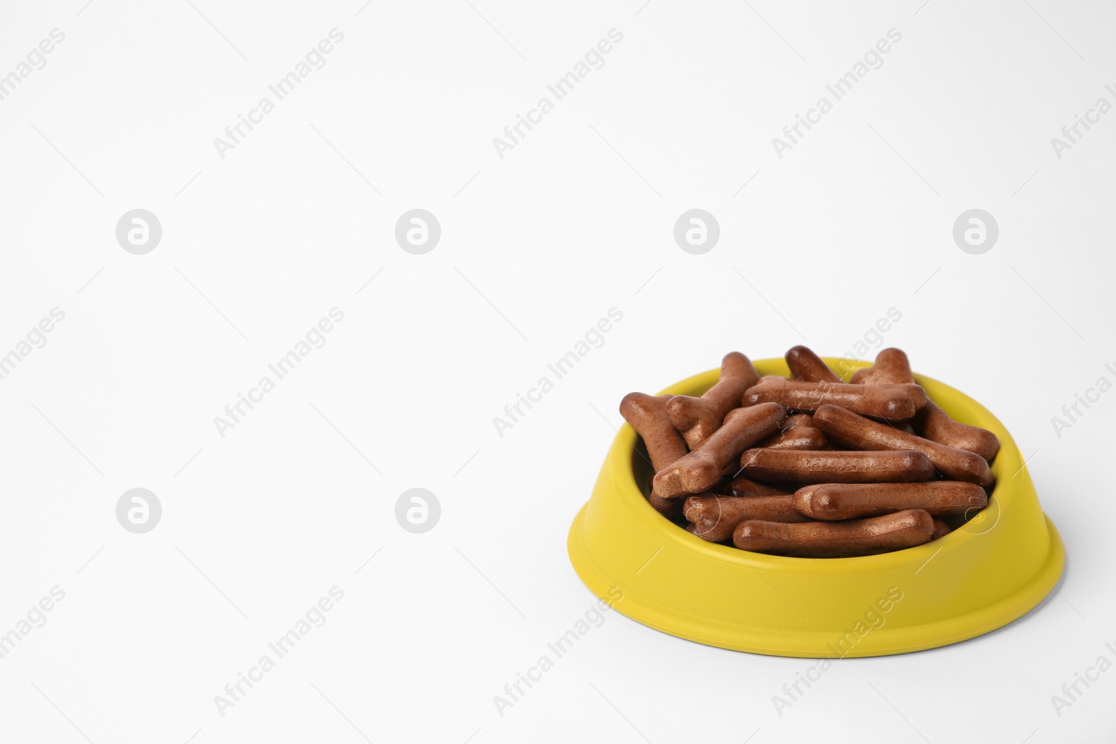 Photo of Yellow bowl with bone shaped dog cookies on white background, space for text