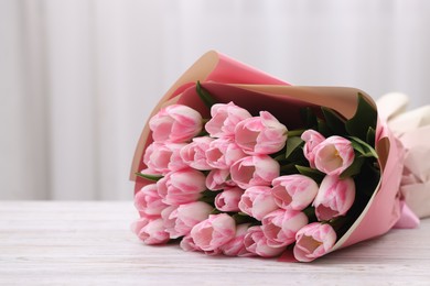 Beautiful bouquet of fresh pink tulips on white wooden table indoors. Space for text