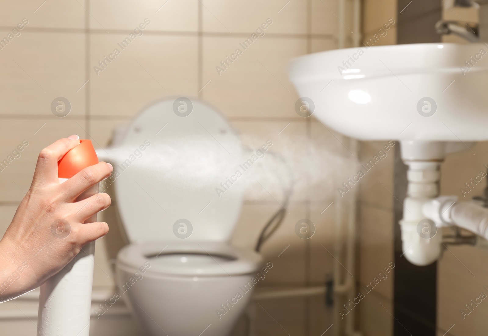 Photo of Woman spraying air freshener in bathroom