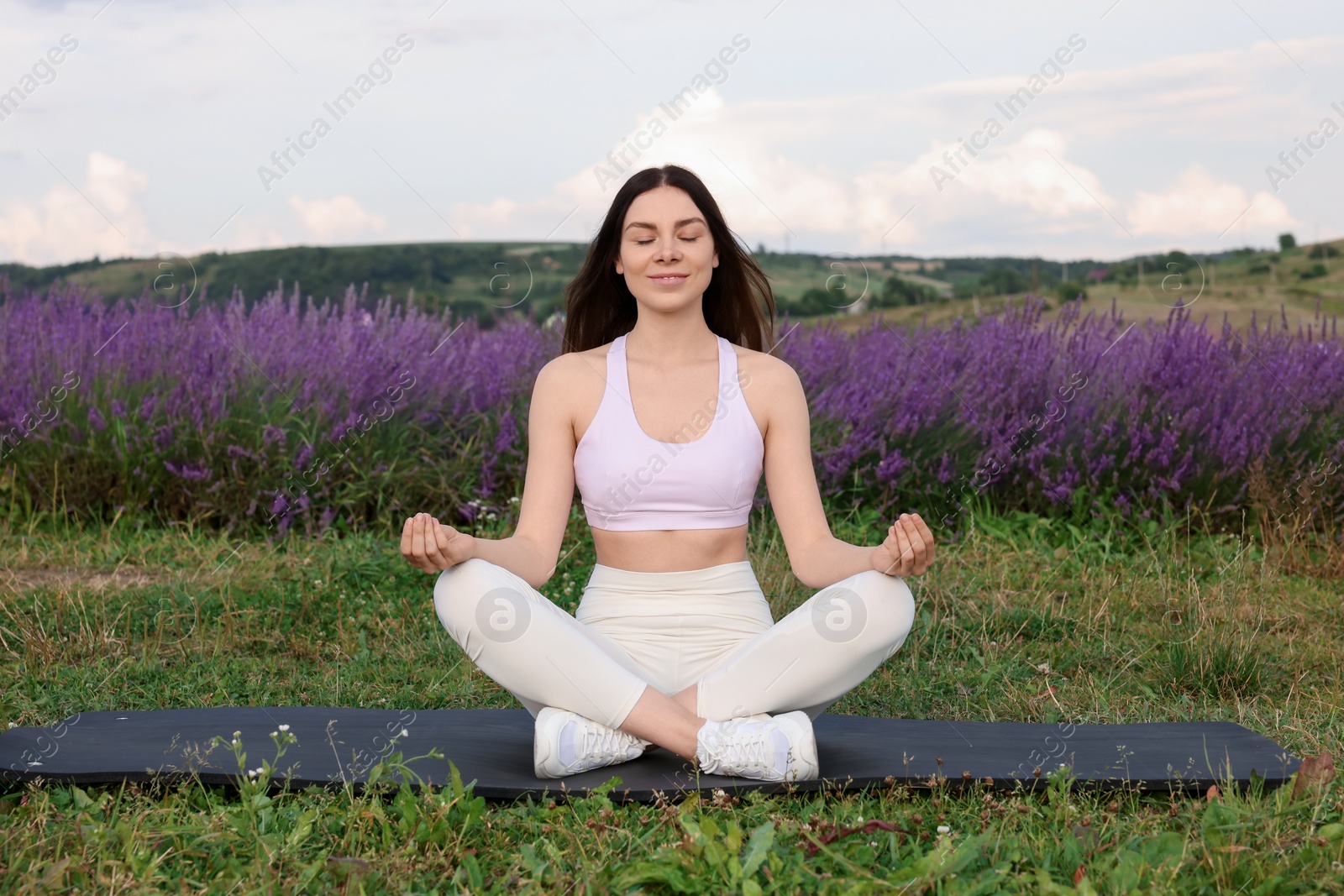 Photo of Smiling woman practicing yoga near lavender outdoors