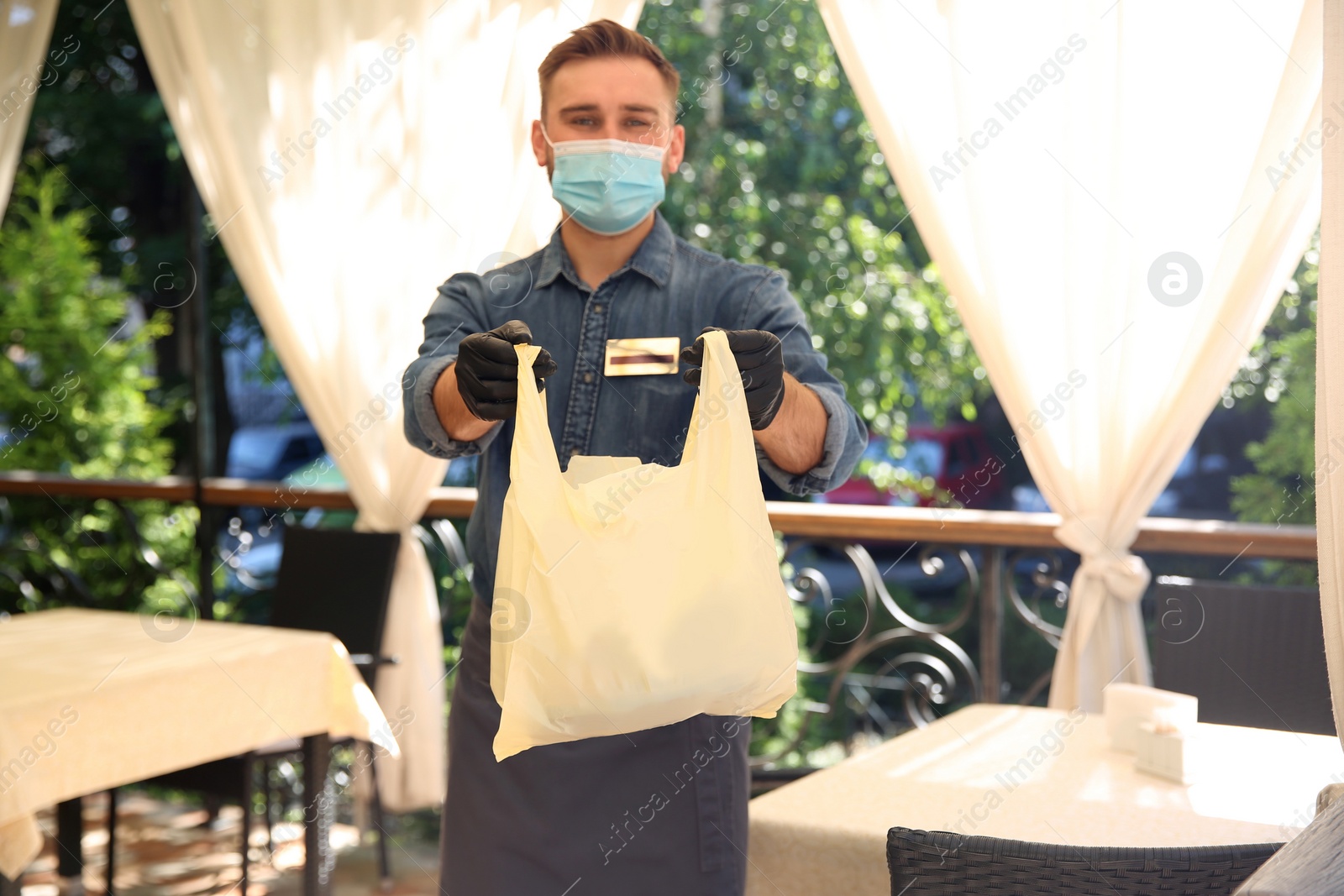 Photo of Waiter with packed takeout order in restaurant. Food service during coronavirus quarantine